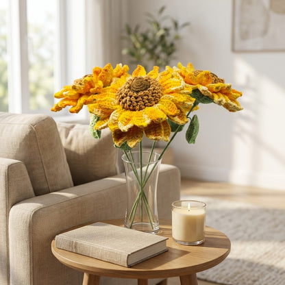 Crocheted sunflowers in a vase on a wooden table with a candle and book, in a bright living room