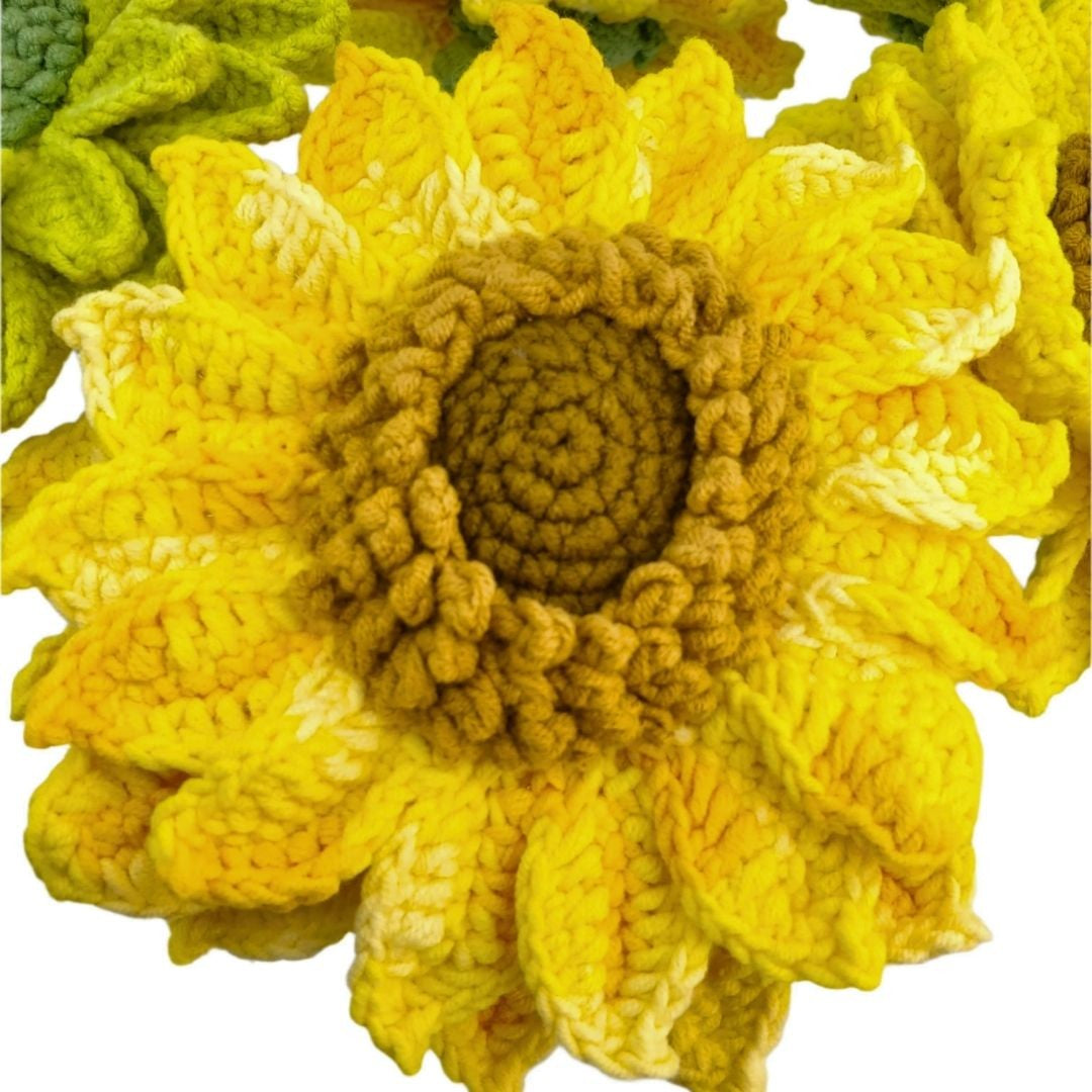 Crocheted sunflower with a green leaf on a white background