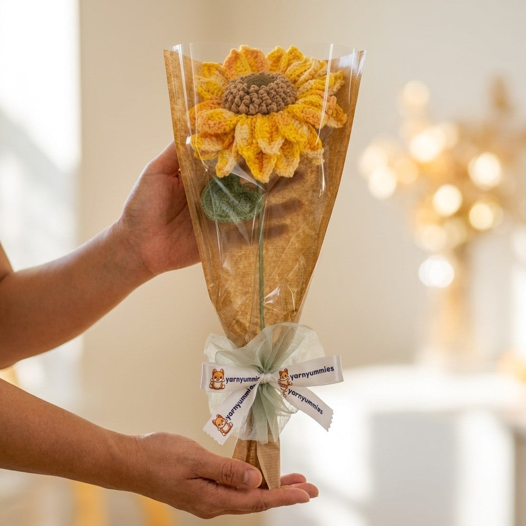 Bouquet of sunflowers wrapped in brown paper with a white ribbon held by a person.