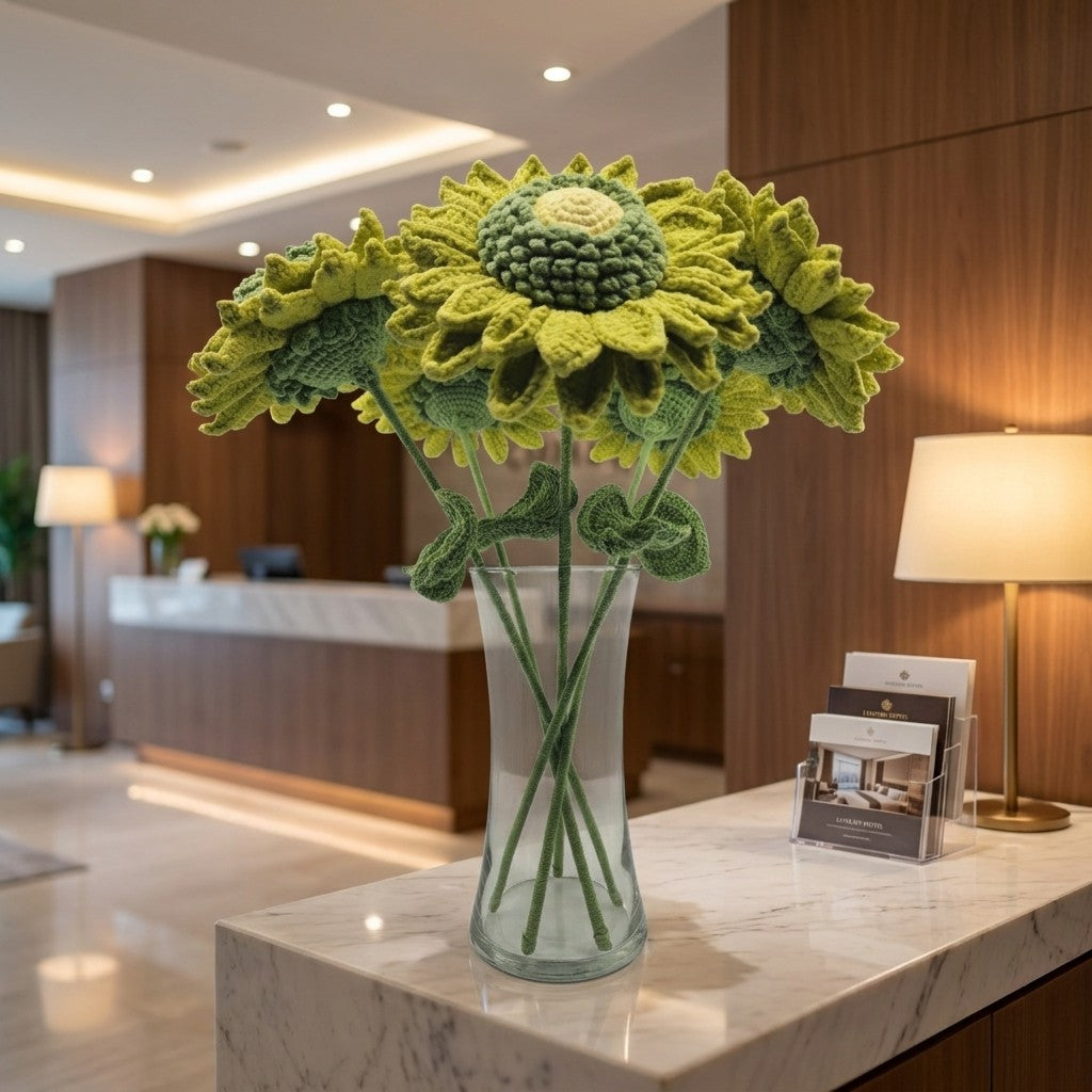 Knitted sunflowers in a glass vase on a marble counter in a modern interior setting.