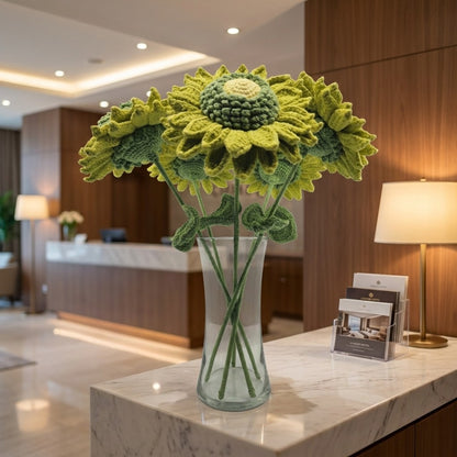 Knitted sunflowers in a glass vase on a marble counter in a modern interior setting.