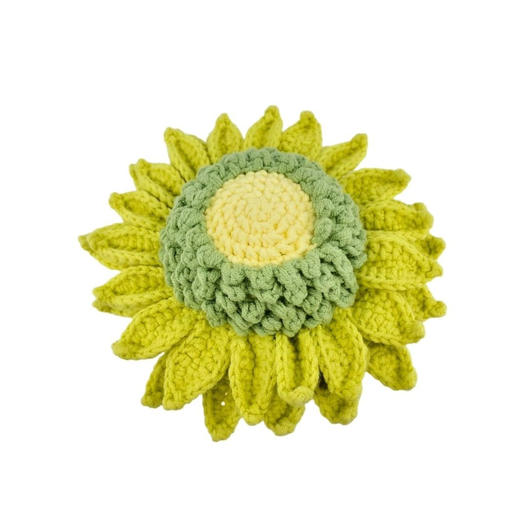 Crocheted sunflower with green leaves on a white background