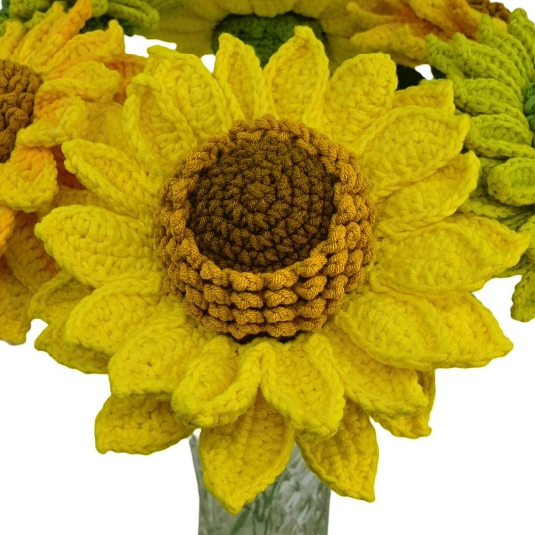 Close-up of a crocheted sunflower with a clear vase on a white background