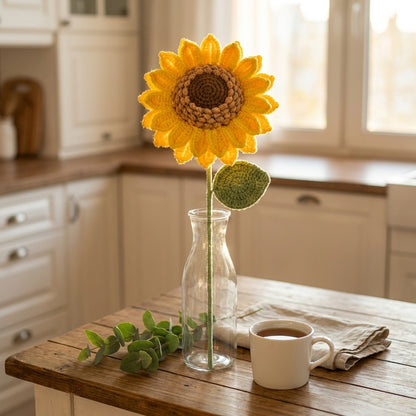 Sunflower in a glass vase on a wooden table with a cup of coffee in a kitchen.