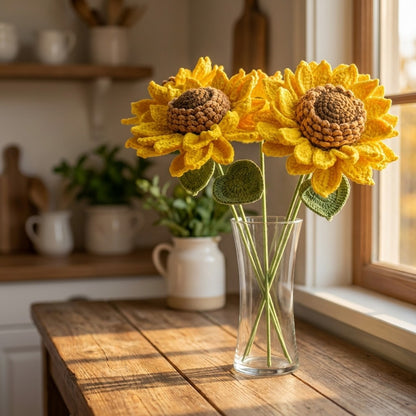 Knitted sunflowers in a glass vase on a wooden table with a kitchen background