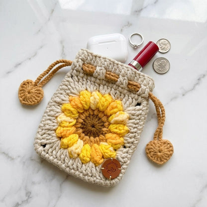 Crocheted pouch with sunflower design on a marble surface