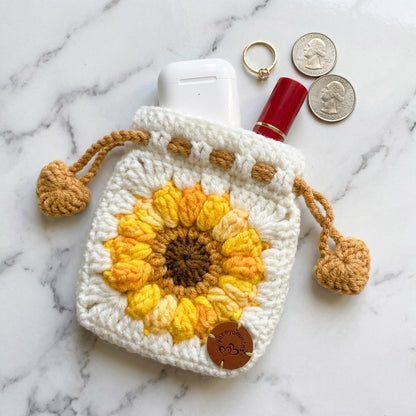 Crocheted pouch with sunflower design on a marble surface