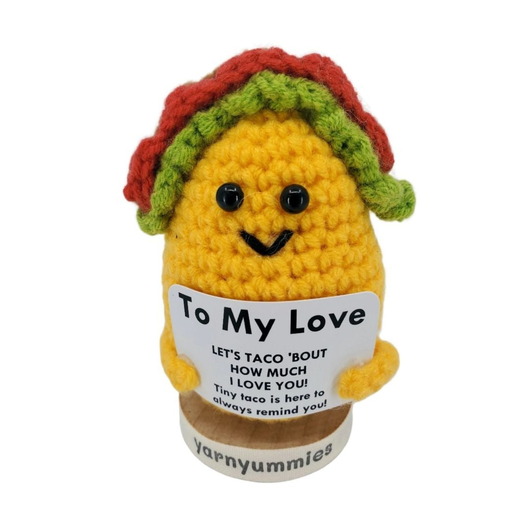 Crocheted taco-shaped toy with a message on a white background