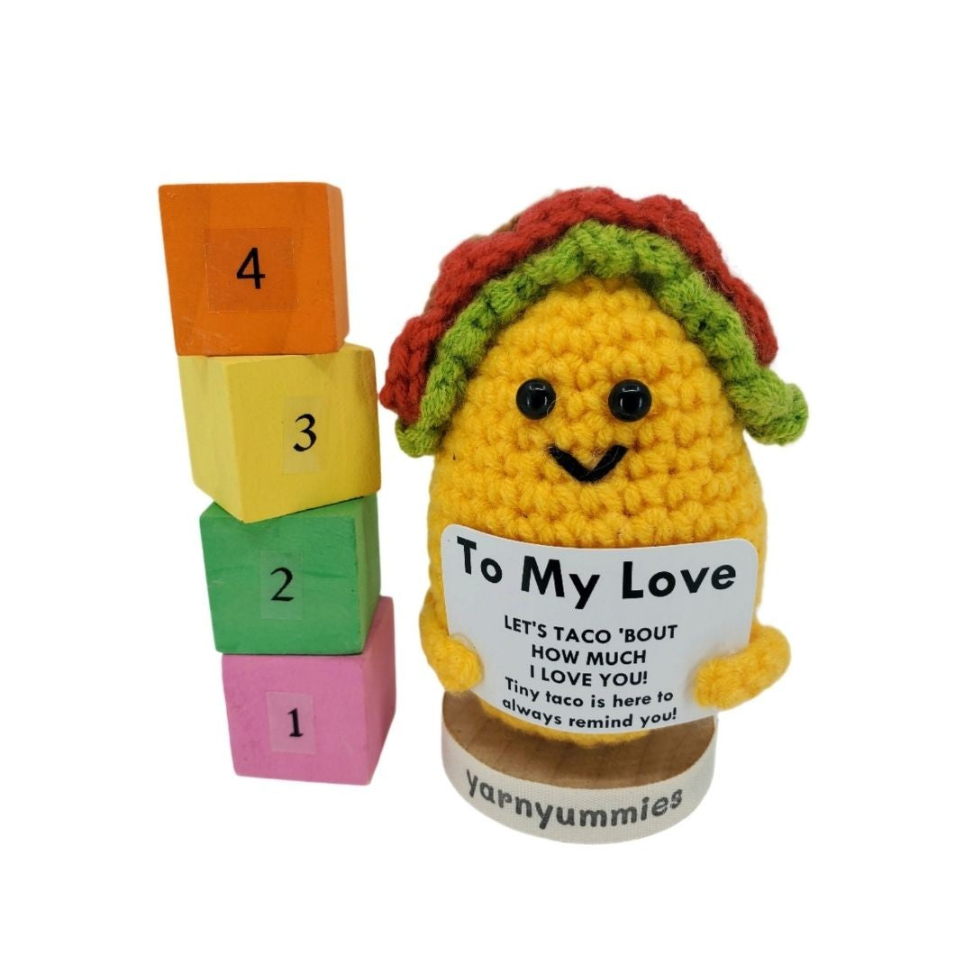 Crocheted taco toy with a message and stack of colorful blocks on a white background