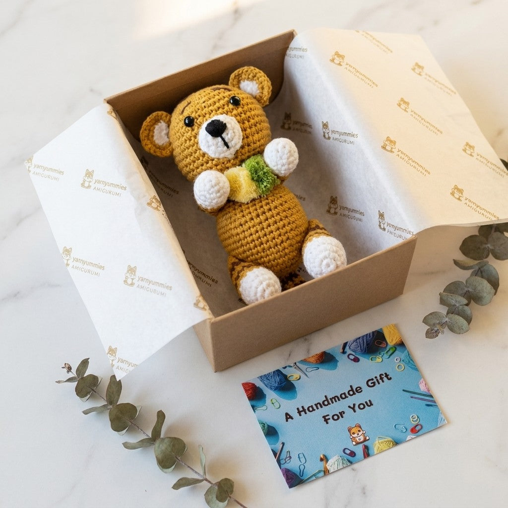 Crocheted small tiger in a box with a 'Handmade Gift For You' card on a light surface.