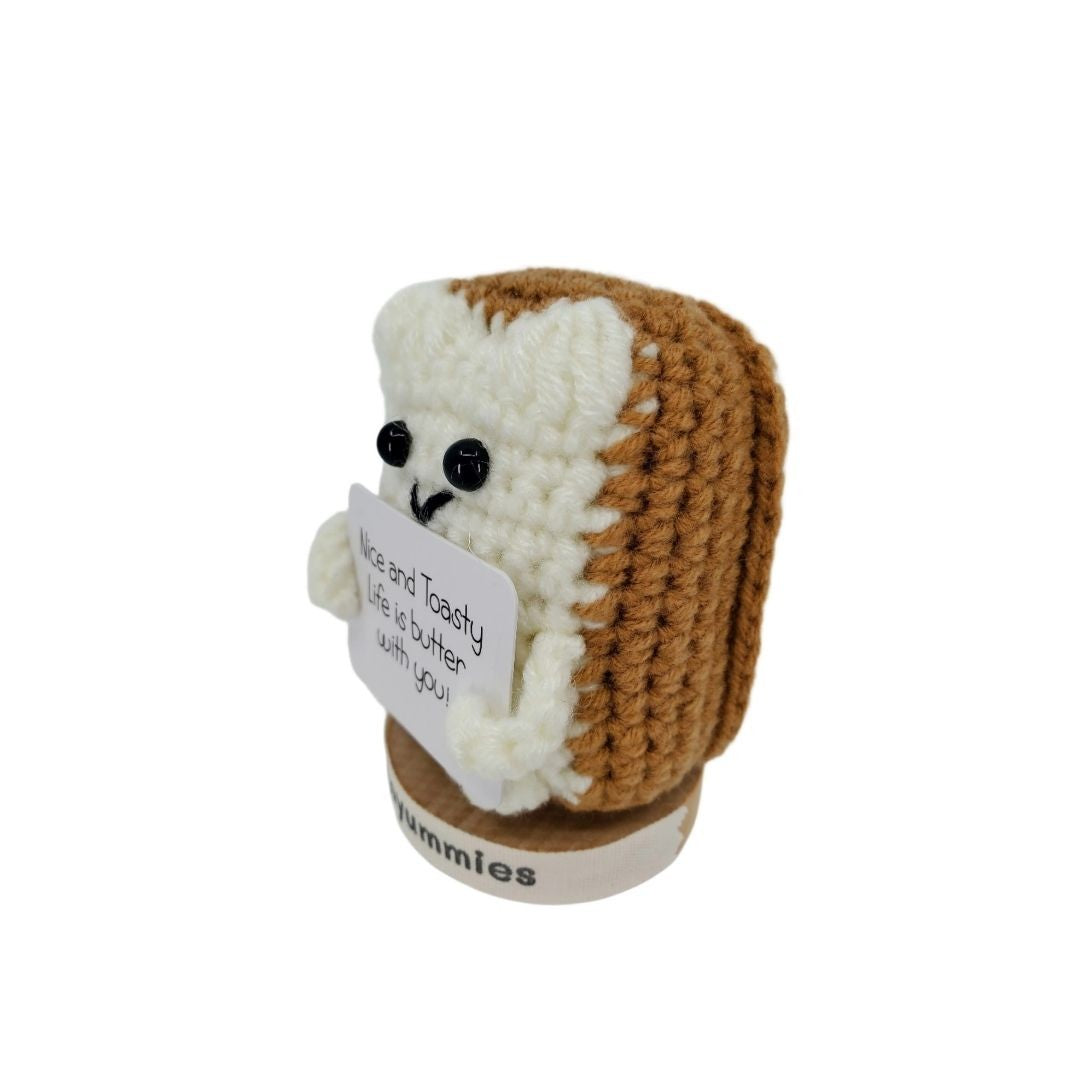 Crocheted bread toast character plush holding a sign with text on a white background