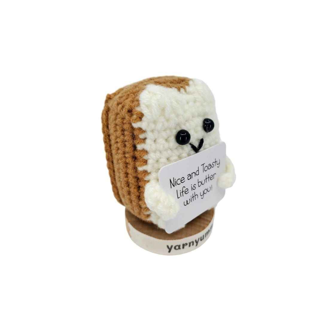 Crocheted bread plush with a sign on a white background