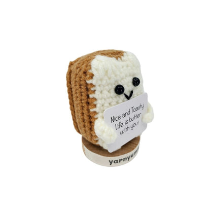 Crocheted bread plush with a sign on a white background