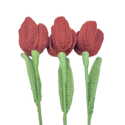 Three red crocheted tulips with green stems on a white background