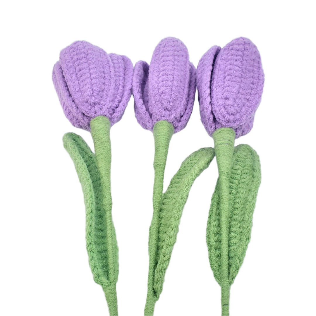 Three purple crocheted tulips with green stems on a white background