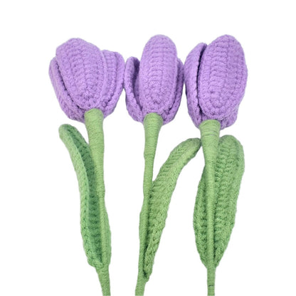 Three purple crocheted tulips with green stems on a white background