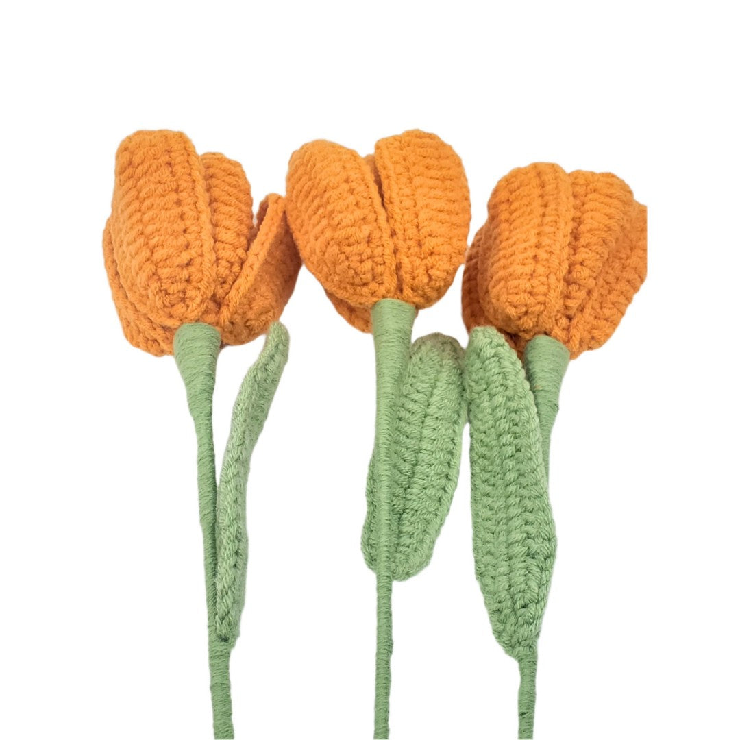 Three crocheted orange tulips with green stems on a white background