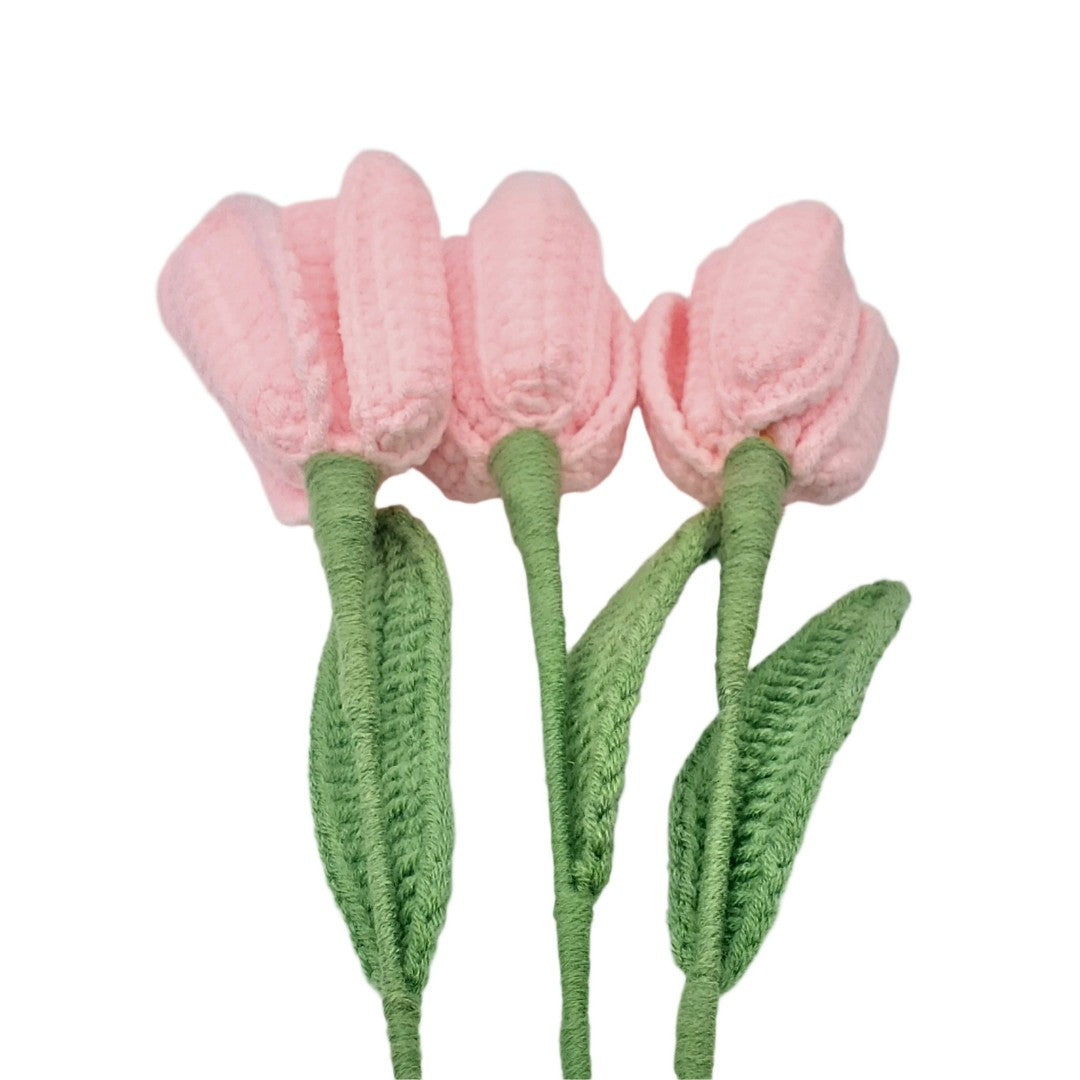 Crocheted pink tulips with green stems on a white background