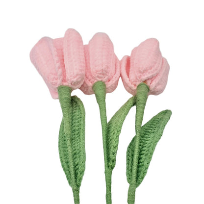 Crocheted pink tulips with green stems on a white background