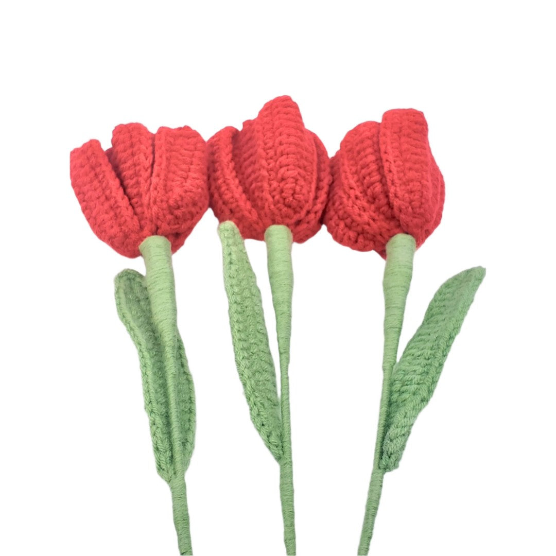 Three red crocheted tulips with green stems on a white background