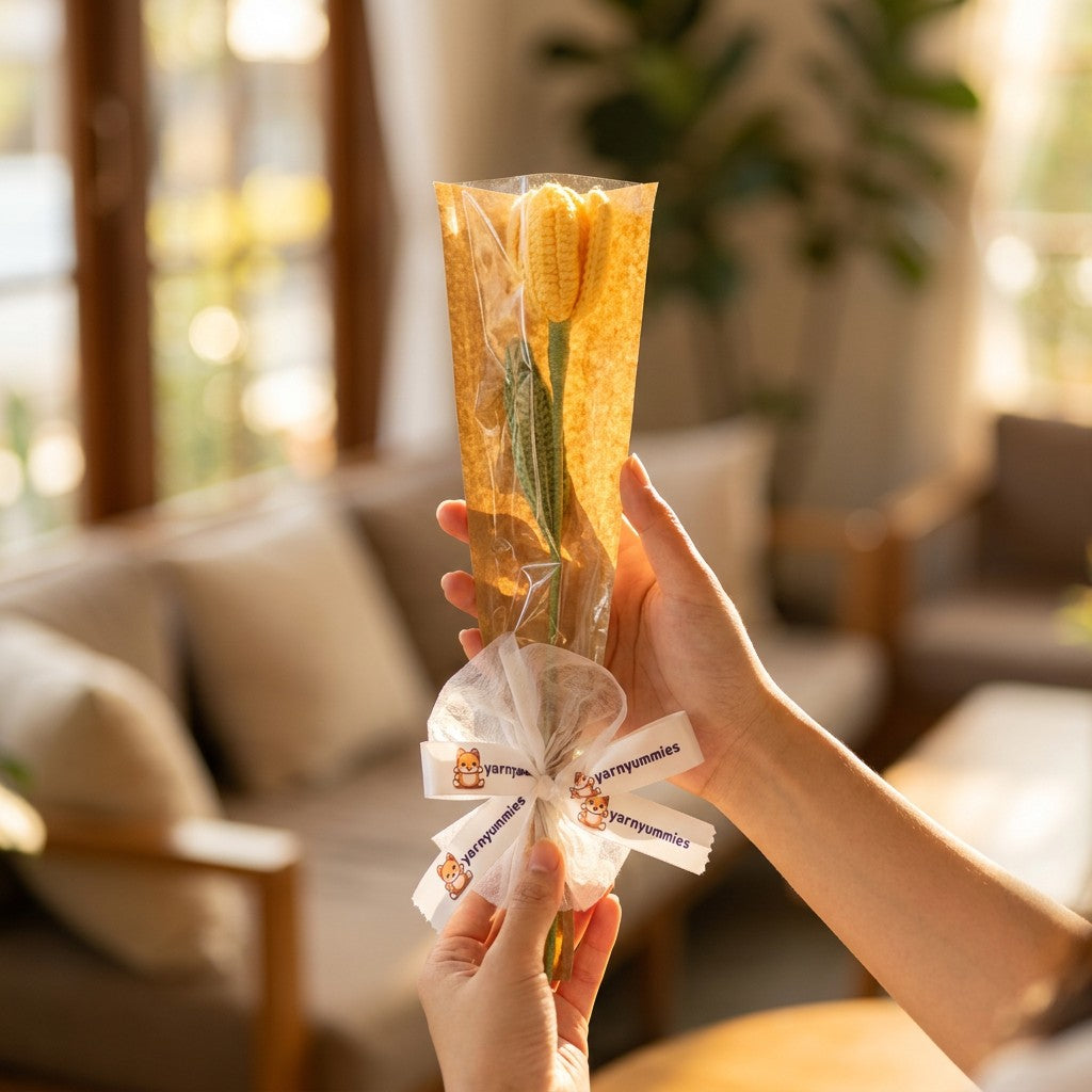 Person holding a bouquet of crocheted tulip with decorative ribbons in a living room setting.