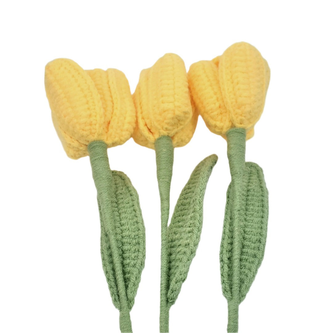 Three yellow crocheted tulips with green stems on a white background