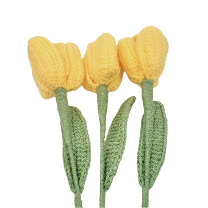 Three yellow crocheted tulips with green stems on a white background