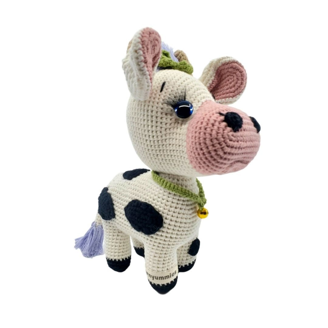Crocheted cow plushie with black spots on a white background