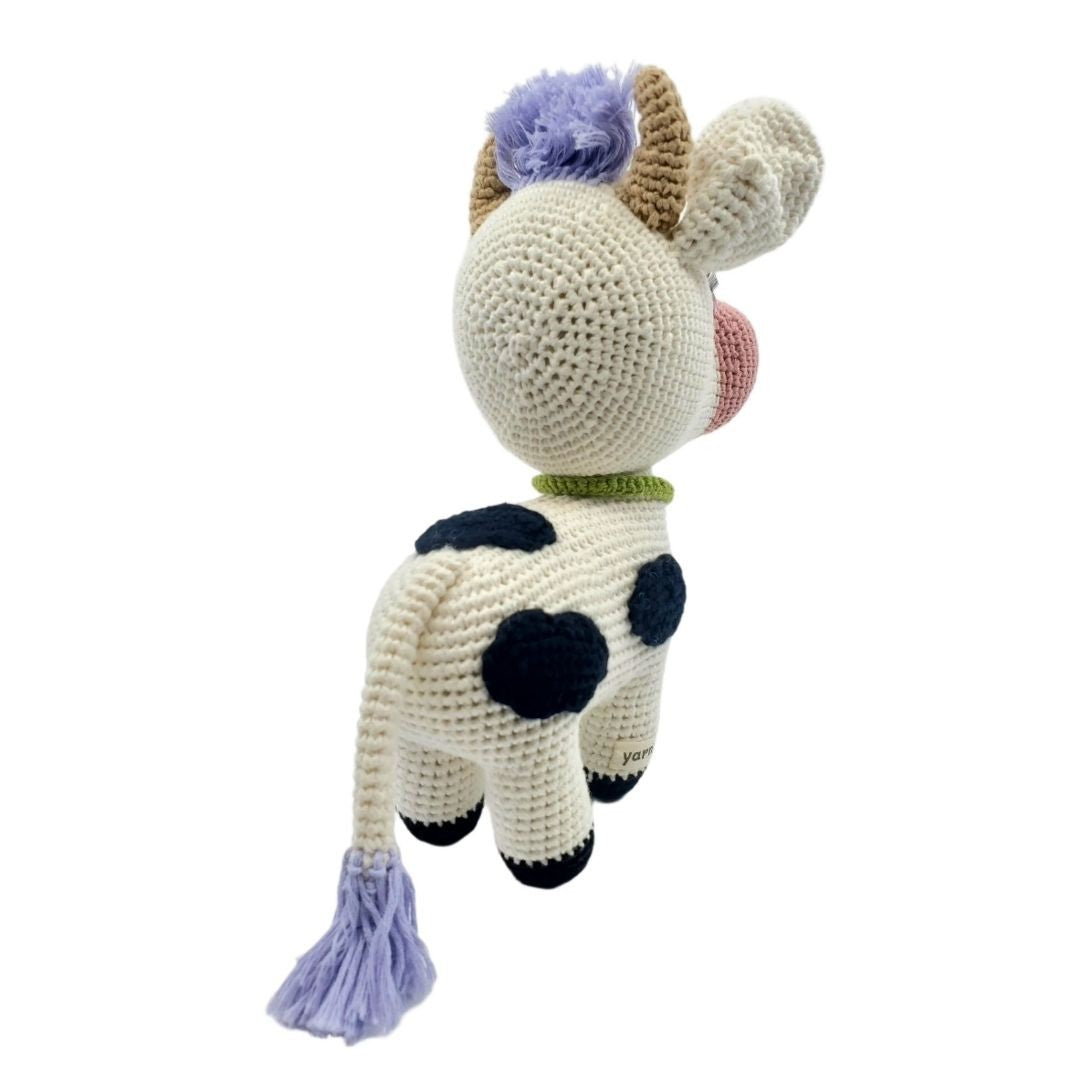 Crocheted cow plushie with black spots on a white background
